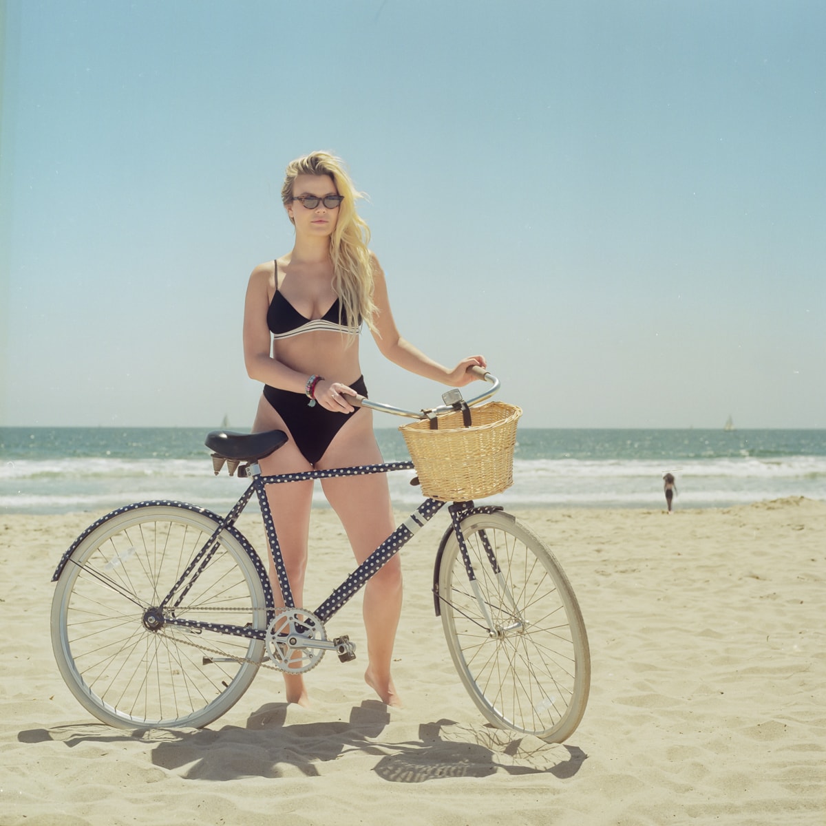 A portrait of a woman with her bike on the beach