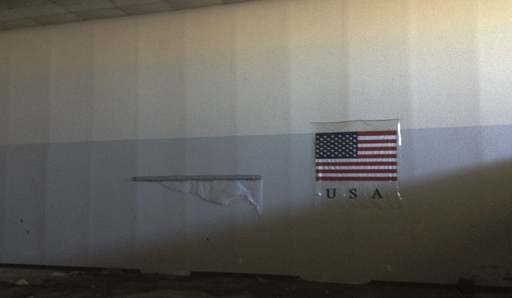 A plastic American flag hung on a huge empty wall