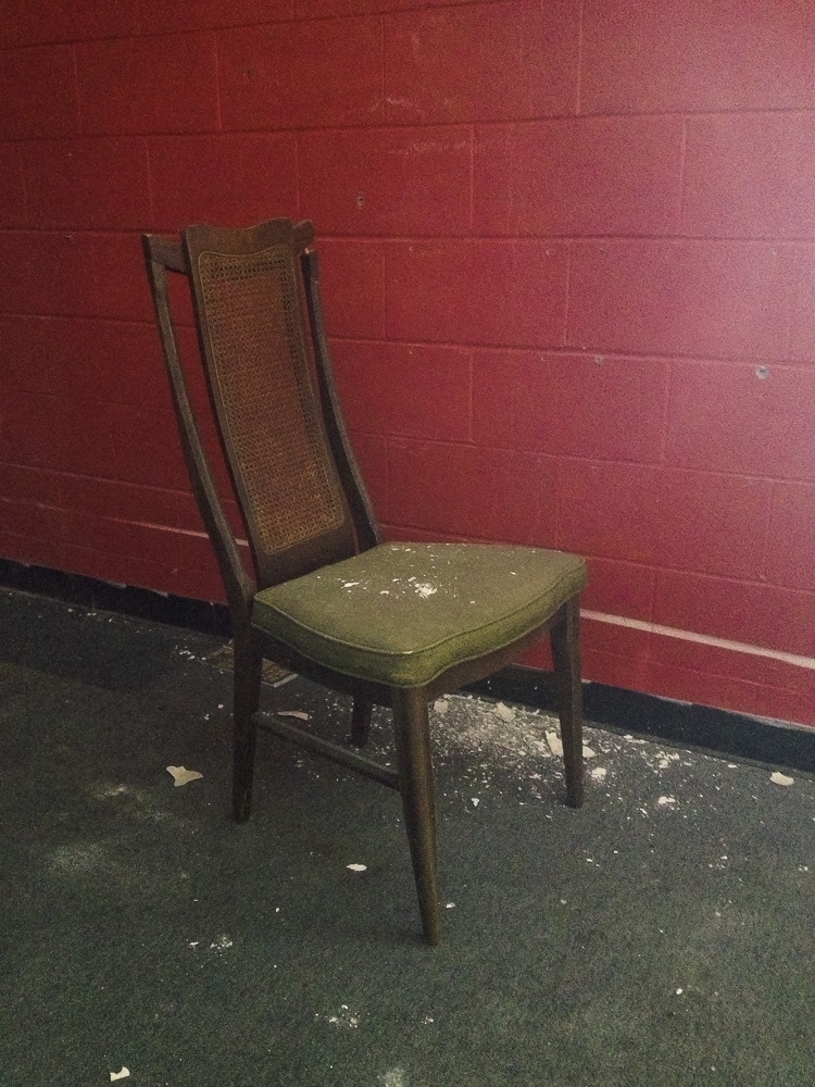 An old chair with dry wall on it that fell from the ceiling