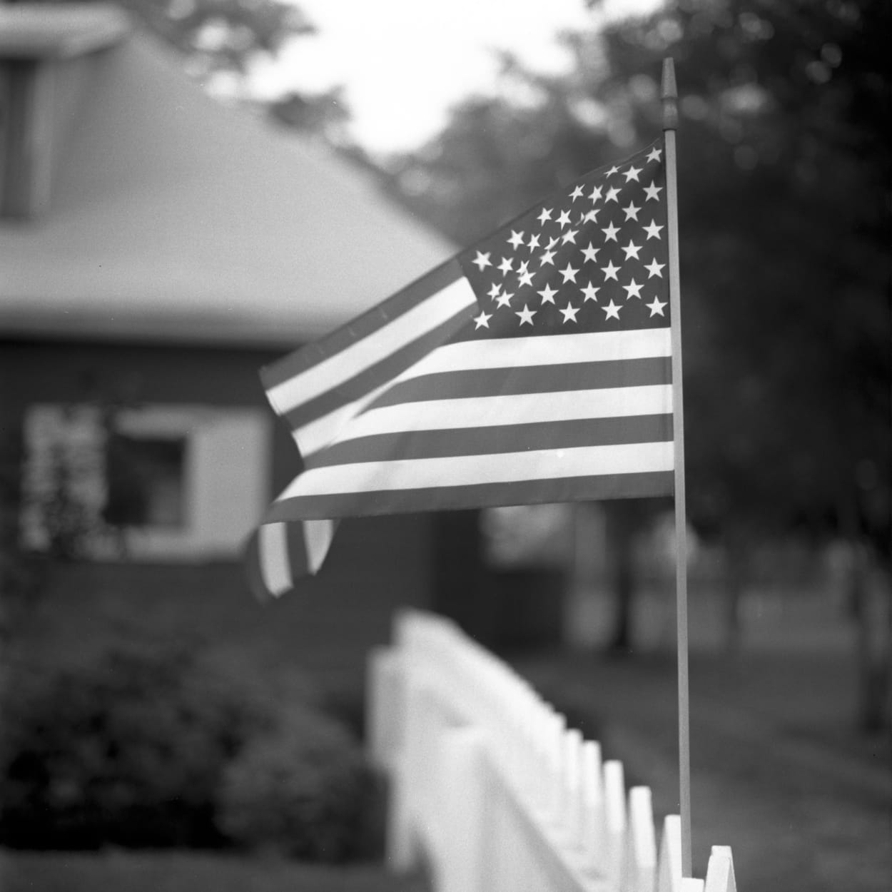 The American flag on the fence of an old house 