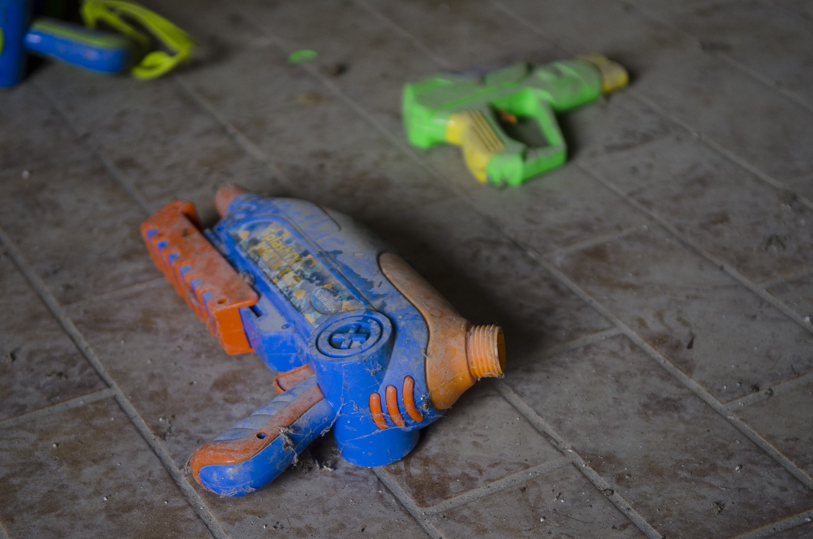 A dusty toy gun on the ground in an abandoned house