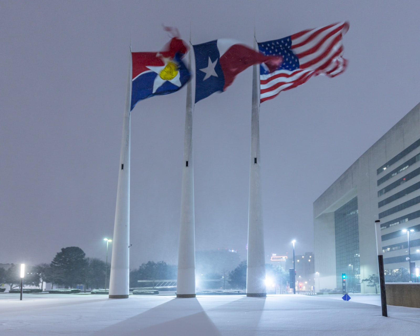 City of Dallas flag, Texas flag, and United States Flag blowing a snowstorm