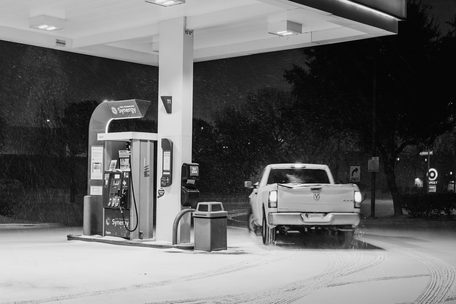 A pickup truck leaving the gas station at night in a snowstorm