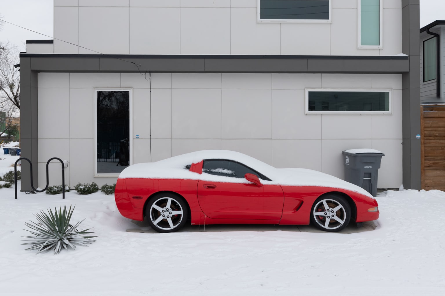 A red corvette partially buried with snow