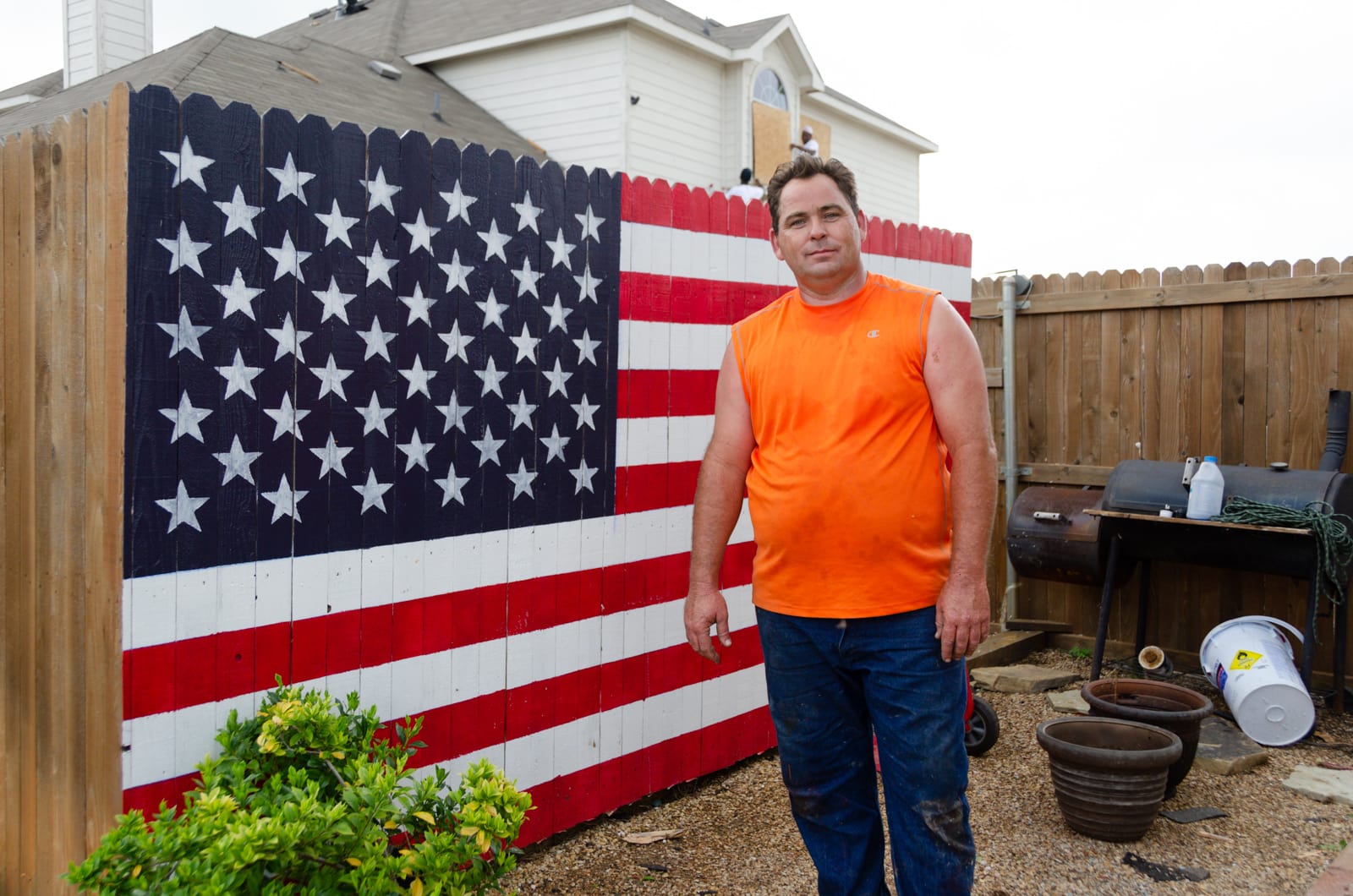 Man in front of his American flag painted fence