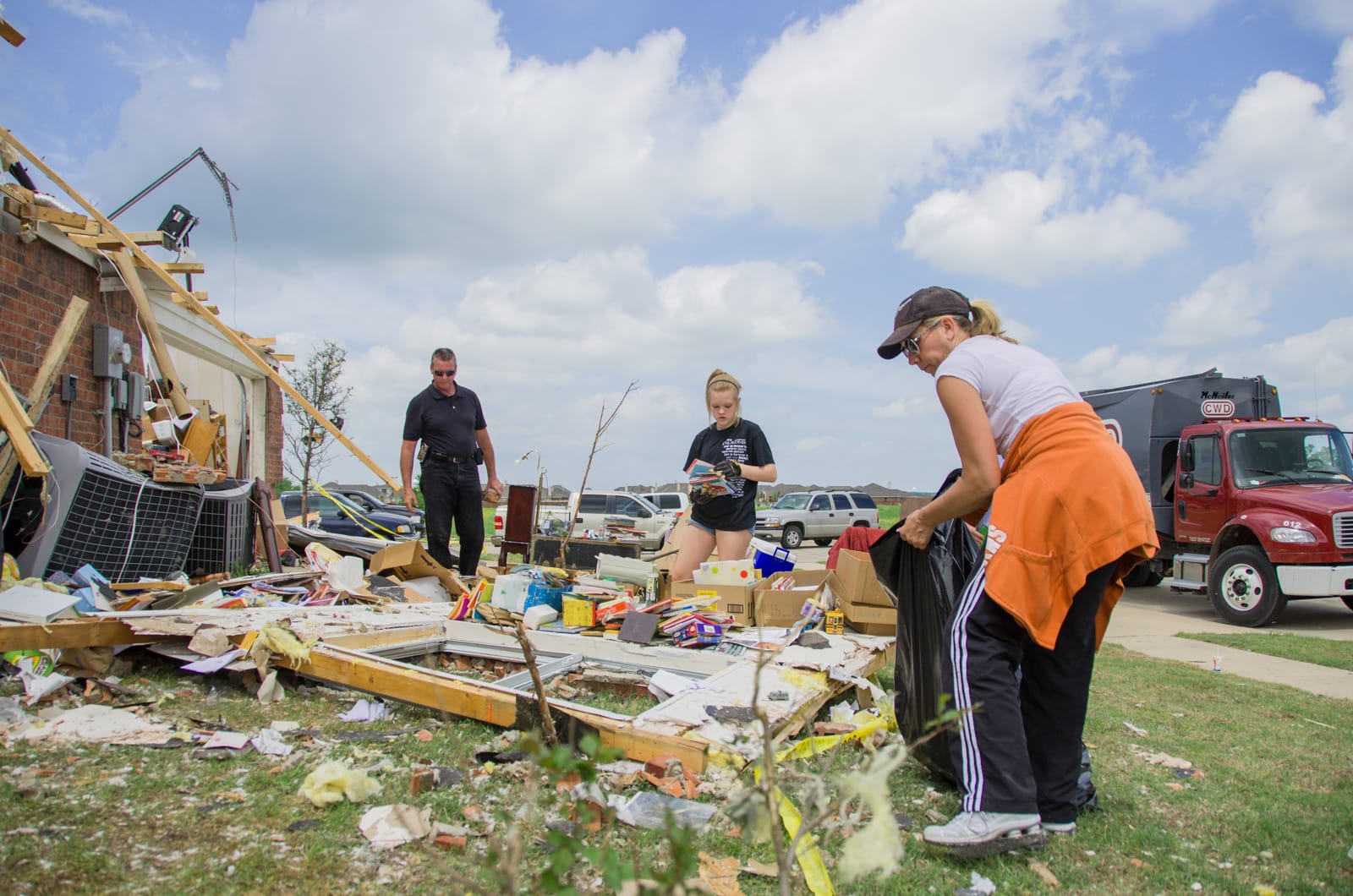 A family cleaning up tornado debris after their home was hit