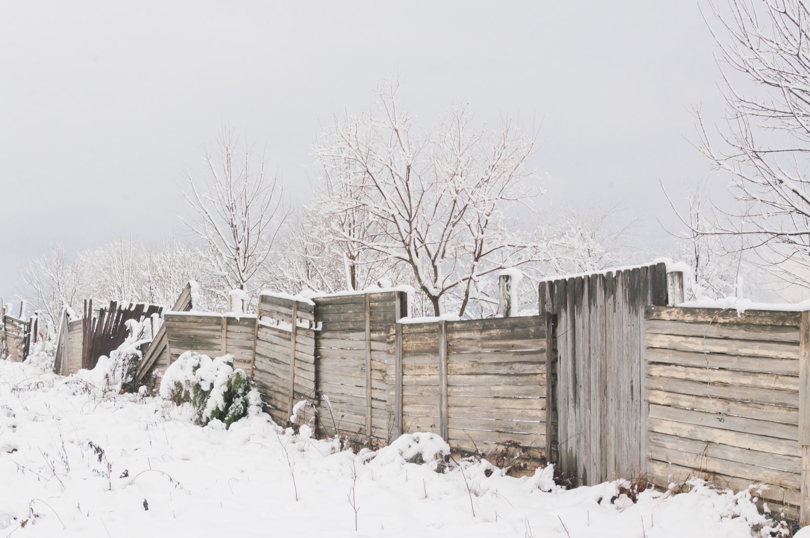A hodgepodge country fence in the snow 