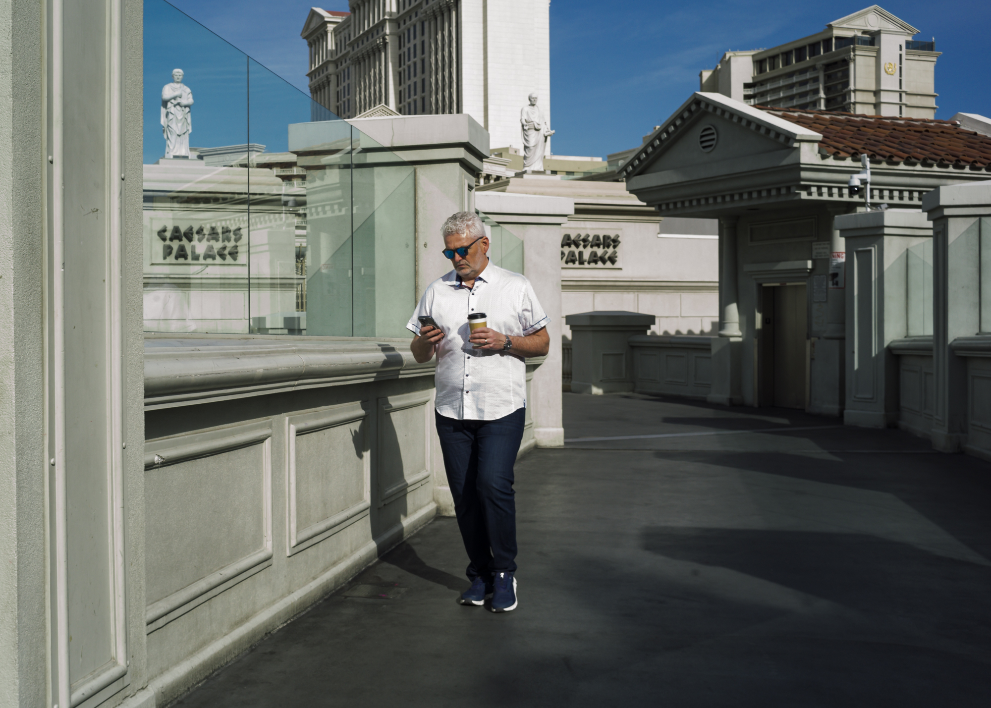 A man walking and checking his cell phone